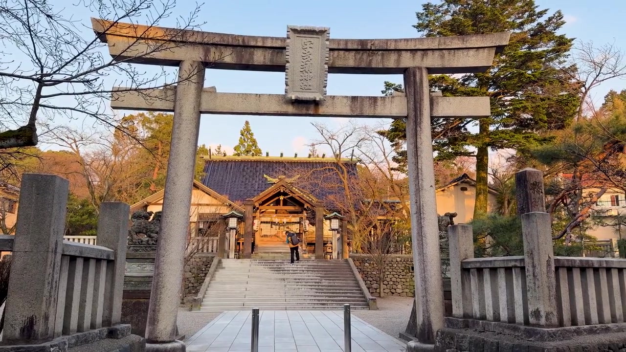 一個廣角平移鏡頭展現了金色光線下的傳統石製鳥居和神社