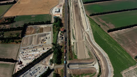 aerial overhead of a train in france as it travels by construction site then into the distance