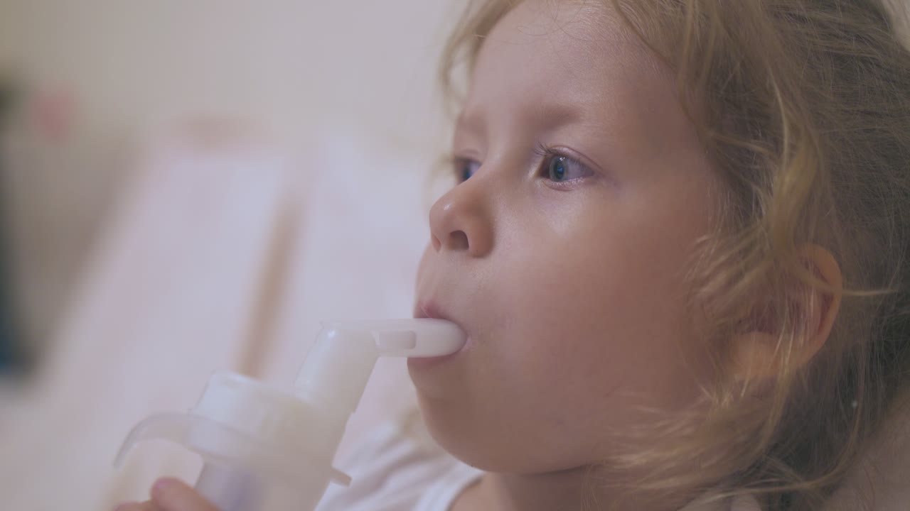 маленькая девочка дышит с ингалятором, лежа в удобной кровати