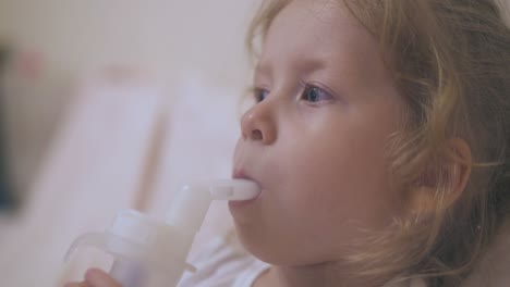 little girl breathes with inhaler lying in comfortable bed