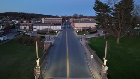 Ascending-drone-shot-of-cars-on-road-in-american-small-town-at-dusk,USA