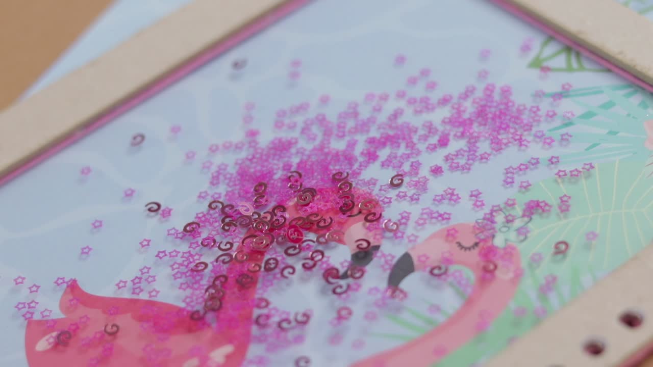 Pink sequins falling on top of hand made notebook, close up