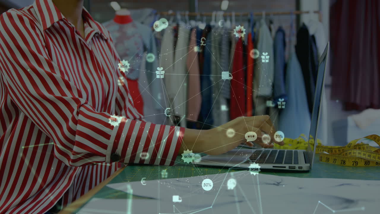 animación del globo de iconos digitales sobre la sección media de la diseñadora de moda femenina usando una computadora portátil