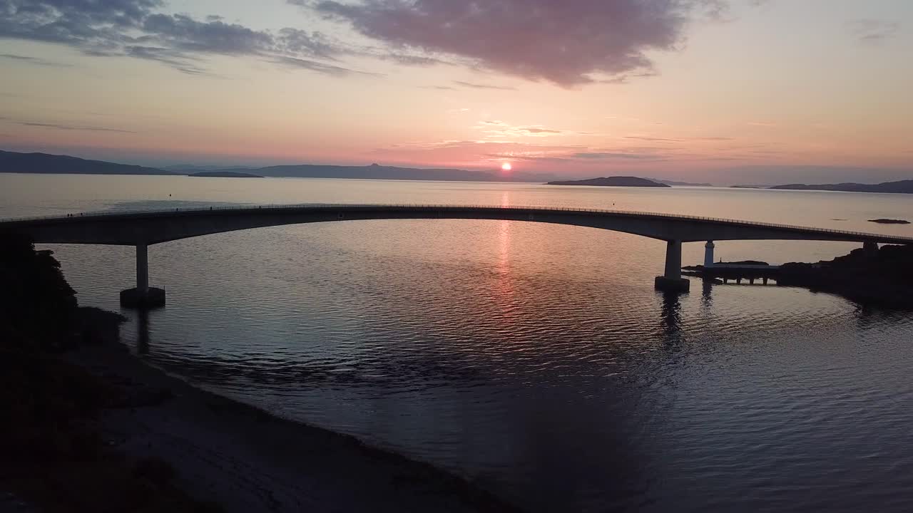 Amazing sunset over coastal sea bridge, calm evening water ripples, aerial view