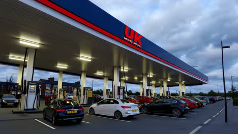 a gas station at dusk with close-ups of fuel pumps and cars