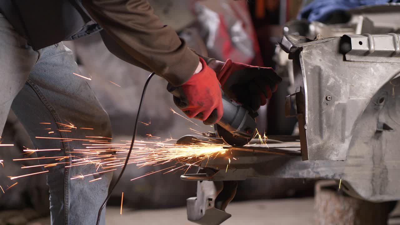 primer plano, manos enguantadas del hombre usando chispas de sierra circular en metal
