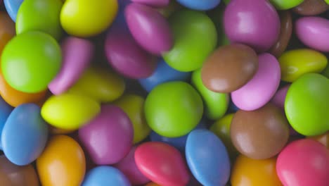 slow motion close-up of round colorful chocolate candies, dragee. rotation and fall multicolored chocolate candies