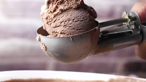 mano recogiendo helado con una cuchara de un plato