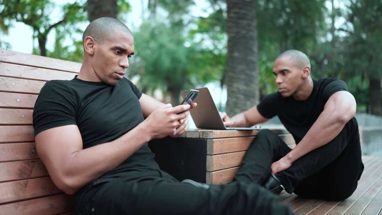 Serious brothers typing on phone and working on laptop