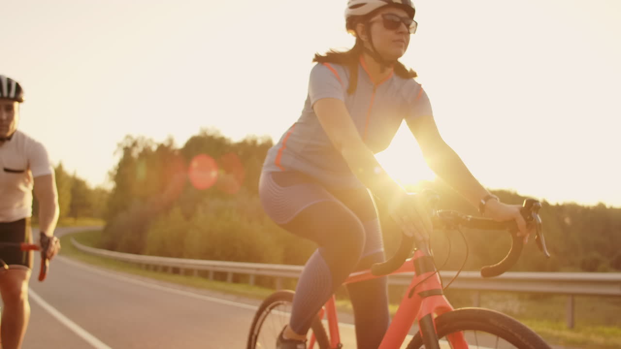 Steadicam shot of mountain biking couple riding on bike trail at sunset doing high.