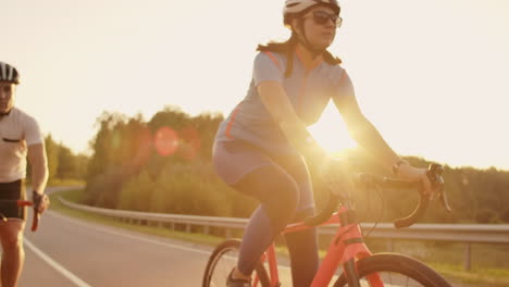 Steadicam-shot-of-mountain-biking-couple-riding-on-bike-trail-at-sunset-doing-high.