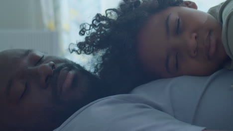 black man falling asleep with little son