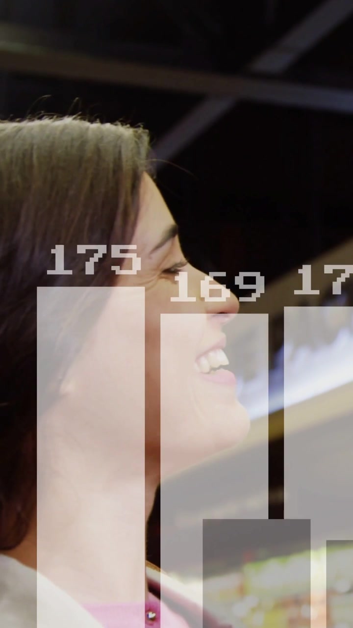 Vertikales Video: Eine Frau, die von einem Lächeln zu Lachen übergeht, während Geschäftsbalken, die Wachstum darstellen, ihren Mantel überlagern.