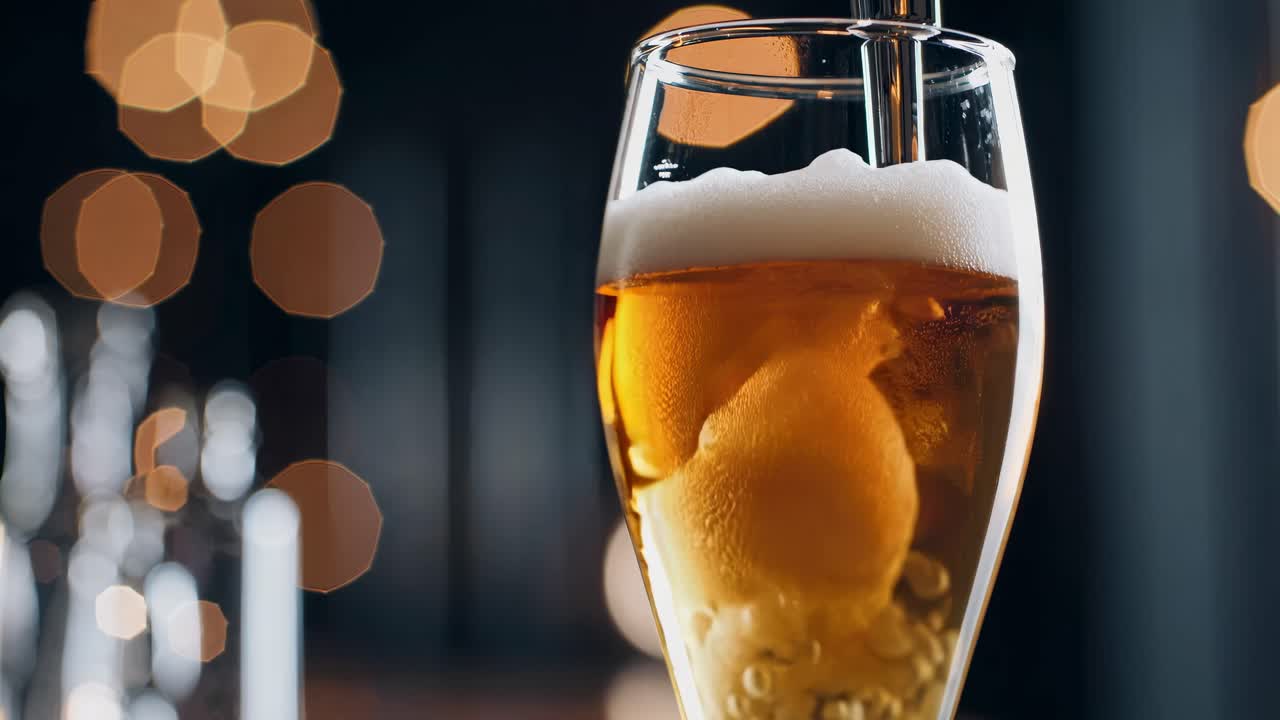Close-up video of a beer glass with bubbles and foam, shot at eye level