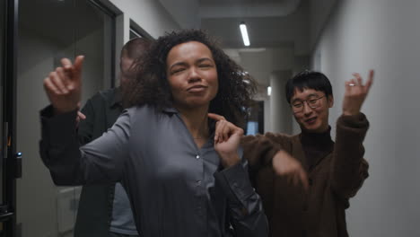 group of colleagues dancing in office hallway