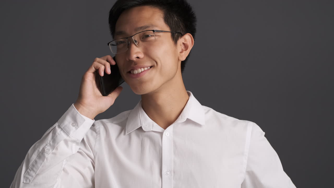 행복한 아시아인 남자가 스마트폰으로 전화합니다.