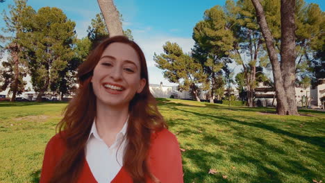 una feliz, atractiva, joven, mujer caucásica en el parque, gira la cabeza hacia la cámara, y deja salir una gran risa