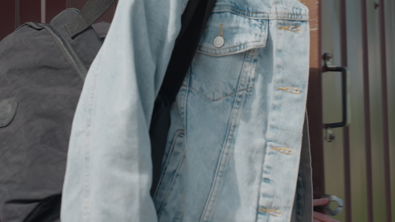 Lady in white crop top opens metal door as woman in red removes sunglasses behind her with another person approaching from background