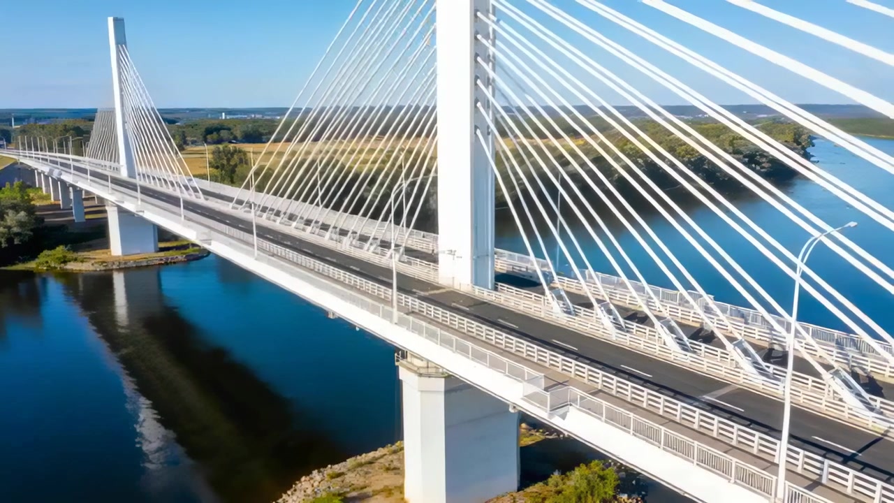 Starting drone sweeping cable-stayed bridge at river crossing, showing central pylon and cables