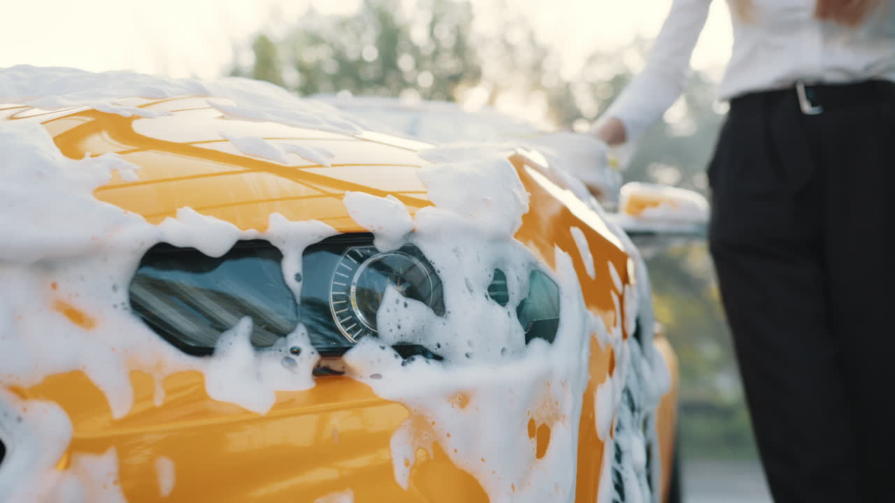 mujer lavando un coche amarillo con espuma