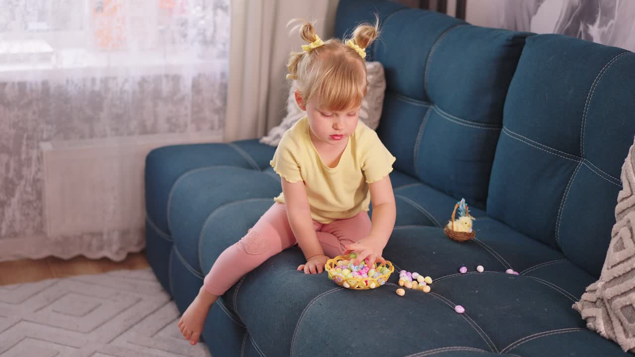 Little Girl Playing with Colorful Candies on a Sofa