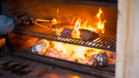 chef at restaurant searing beef picanha and rib eye over grid of grill hoy flames barbecue charcoal oven