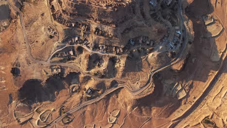 stunning aerial shot of chnenni, tunisia, showcasing the unique desert landscape, ancient agricultural terraces, and a village nestled within the arid terrain.