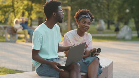 African-American--Friends-Chatting-on-Bench-in-Park