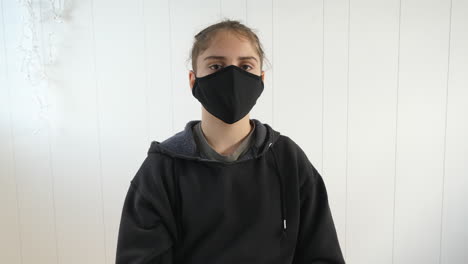 causasian teenager in black hoodie wearing a black anti virus protection mask