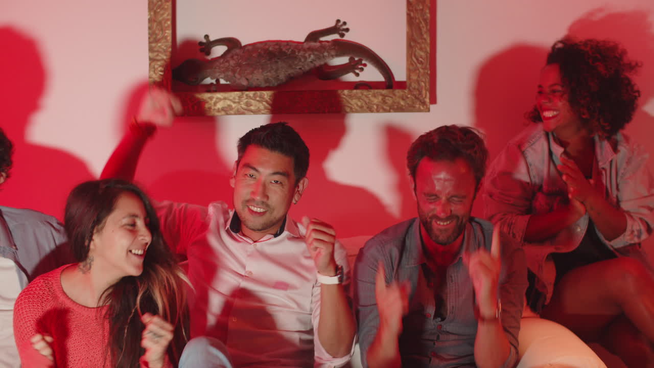 amigos felices viendo el partido en la televisión y regocijándose por el gol