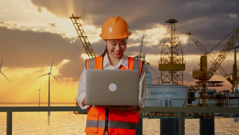 ingeniera que trabaja en una computadora portátil en una granja eólica en alta mar y una plataforma petrolera