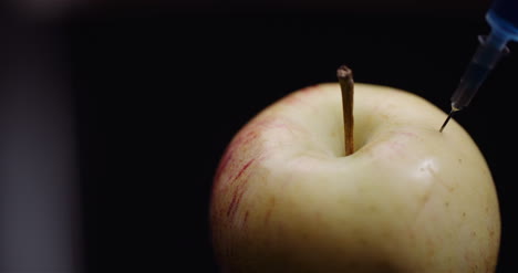 jeringa de modificación genética de alimentos inyectando liqquid en apple concepto de modificación de gmo 3