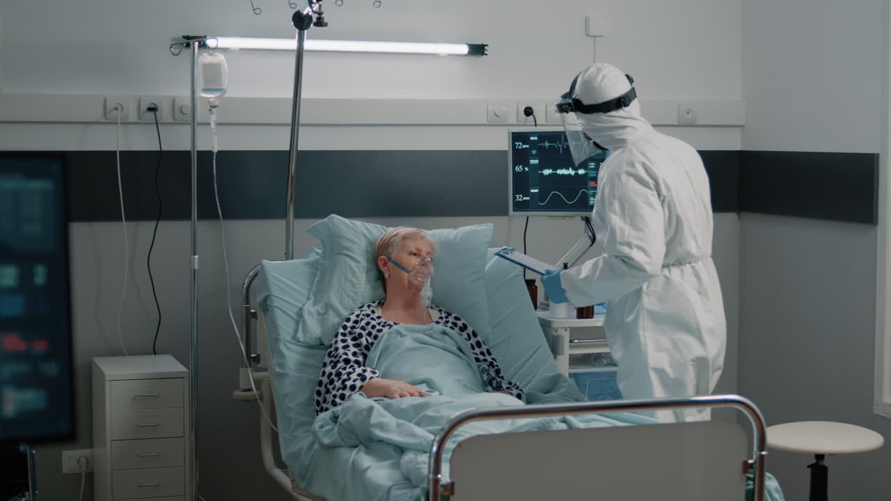 Medic with protective suit checking on heart rate monitor