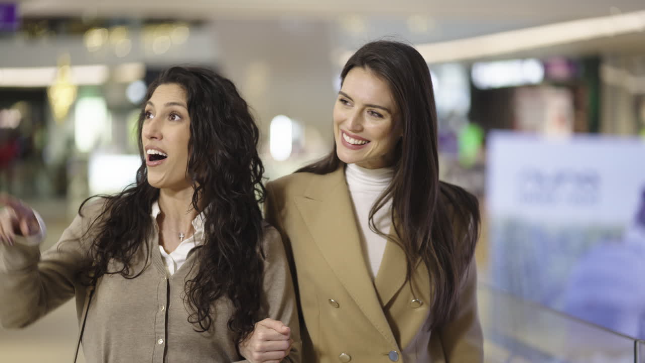 Two Happy Women Walking and Talking in a Shopping Mall