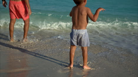 slow motion of a young mexican latin boy playing at the beach in cancun with his father jumping on the water having fun