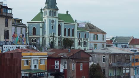 Jib-up-of-picturesque-colorful-houses-and-Lutheran-church-from-Cerro-Alegre-on-a-cloudy-day-in-Valparaiso-city,-Chile