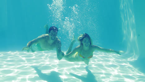 Cute-couple-leaping-into-swimming-pool-holding-hands