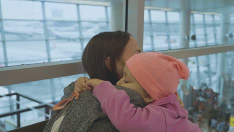 tu madre y tu pequeña hija se abrazan suavemente en el aeropuerto a cámara lenta.