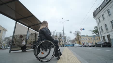 woman in a wheelchair waiting for a bus at a bus stop