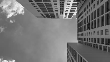 4k black and white time lapse from low angle looking up to architecture and dramatic clouds moving left to right through the scene