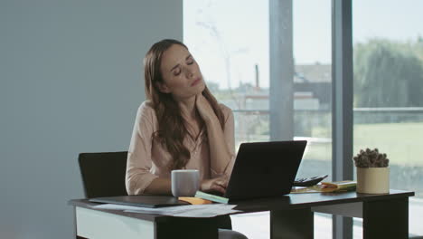 business woman trying to relax in workplace. tired woman working on computer.