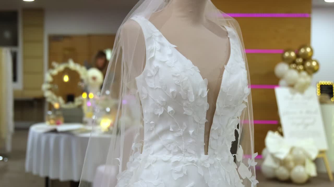 Wide shot of beautiful wedding dress on mannequins at wedding event.