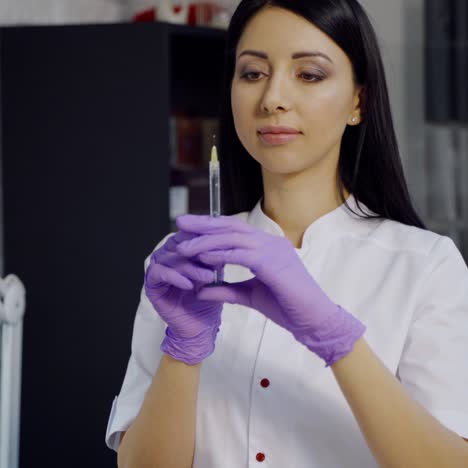 cute cosmetologist with long hair checks a syringe before the botox procedure in the office on the background of a cupboard in a beauty salon.