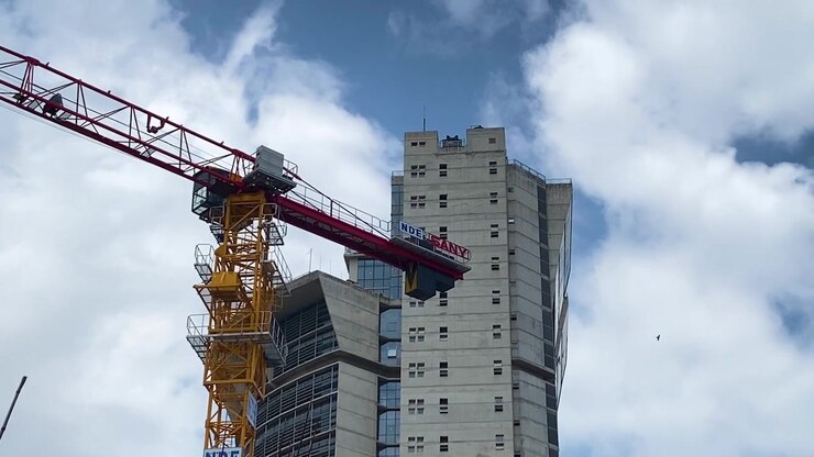 Modern skyscraper building construction by industrial crane under bright blue sky at Dhaka, Bangladesh
