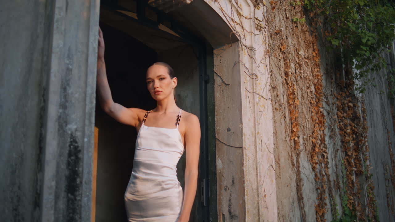 저녁의 빛에 성의 아치에 서있는 소녀, 은 벽을 만지는 감각적인 여성.