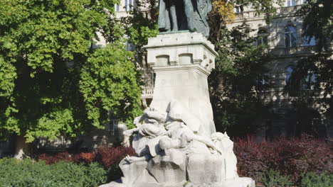 Upward-tilt-shot-of-iron-statue-surrounded-by-flowers-in-gardens-in-Budapest,-Hungary