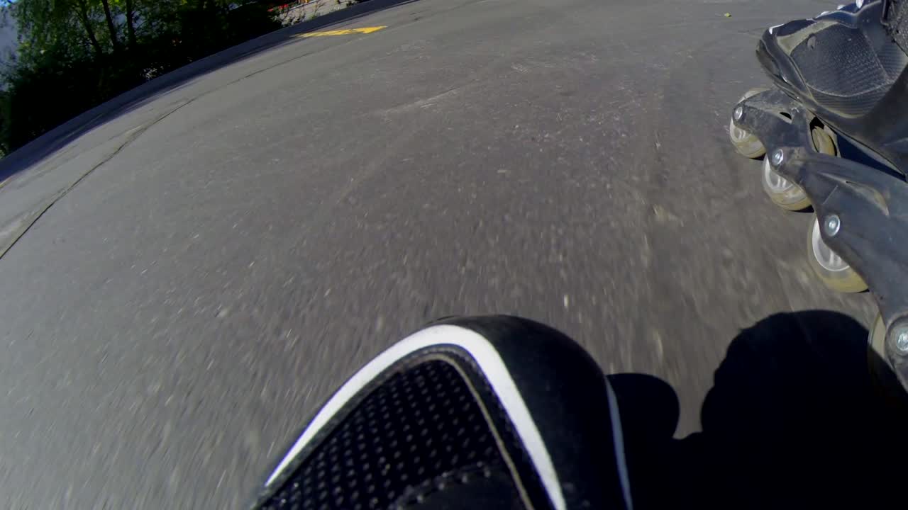 Et nærbillede fra Go Pro af fronten på rulleskøjter, mens en ung mand skøjter rundt på en parkeringsplads