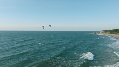 establishing aerial view of a group of people engaged in kitesurfing, sunny summer day, high waves, extreme sport, baltic sea karosta beach , wide drone shot moving forward