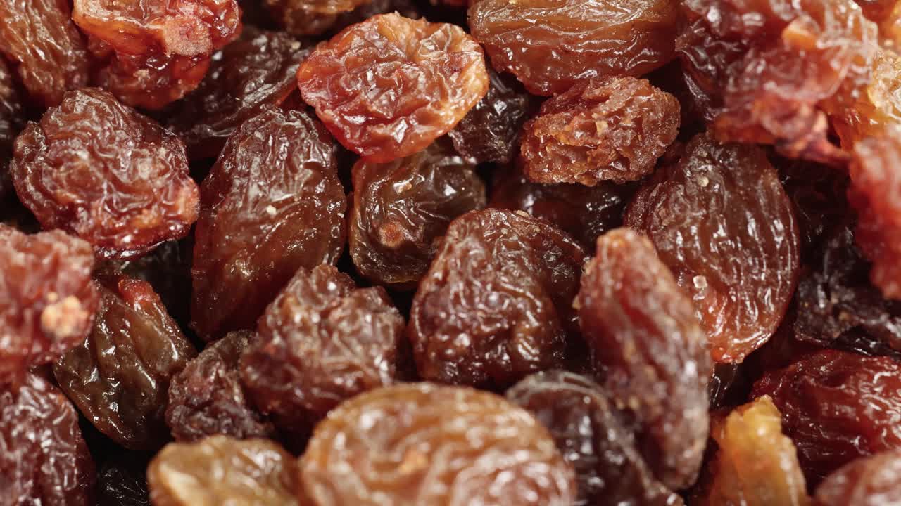 Close-up video of raisins cascading into a pile, highlighting texture and color with warm lighting
