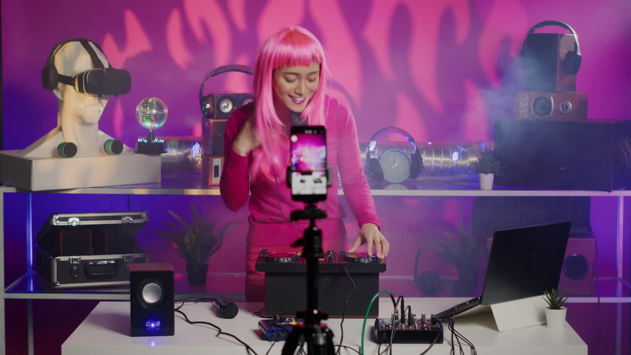DJ with pink wig streaming live music in a neon-lit studio